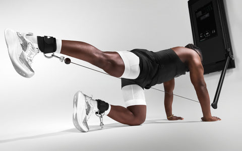 Tonal coach Ackeem Emmons performing a quadruped donkey kick on Tonal using ankle straps.