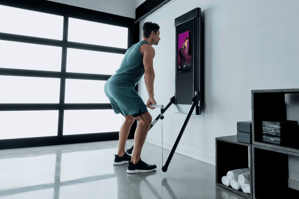A man is working out in his garage, using Tonal to complete an RDL.