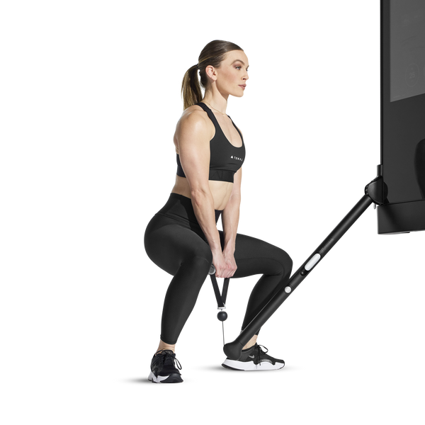Woman performing sumo squat using Tonal machine and a single handle