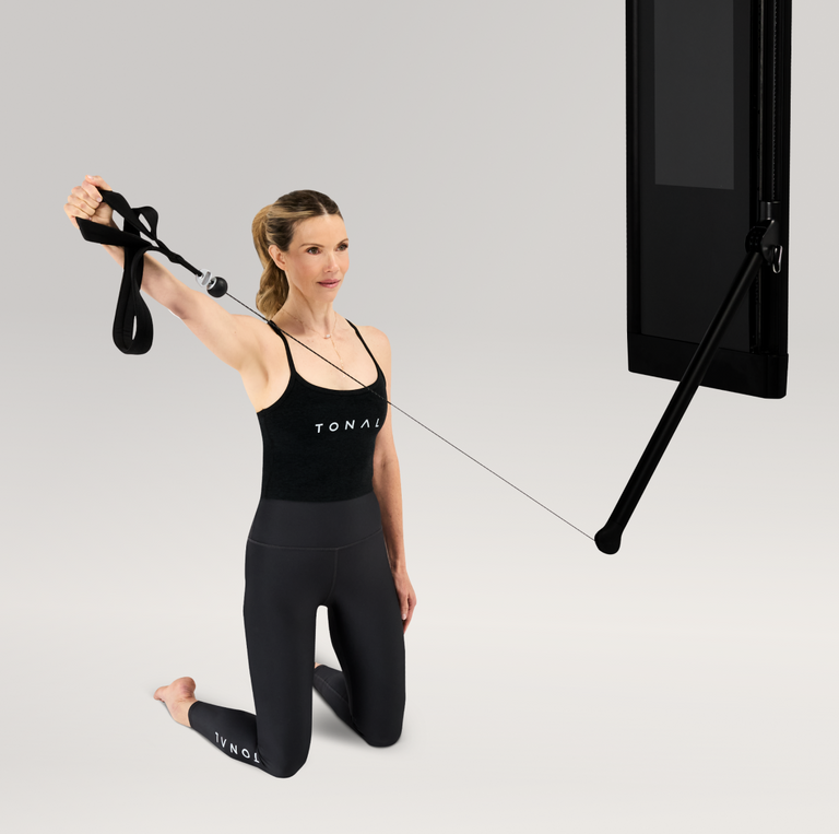Woman exercising using Pilates loops on a Tonal machine