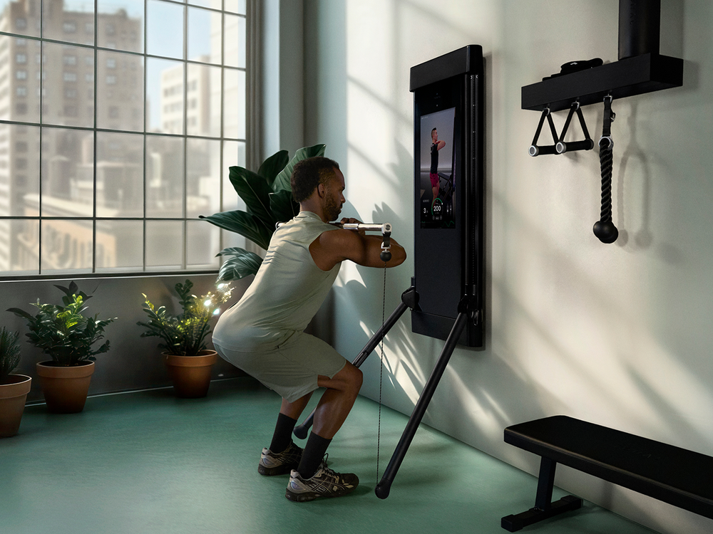 Man using Tonal bar accessory with a Tonal trainer in his home