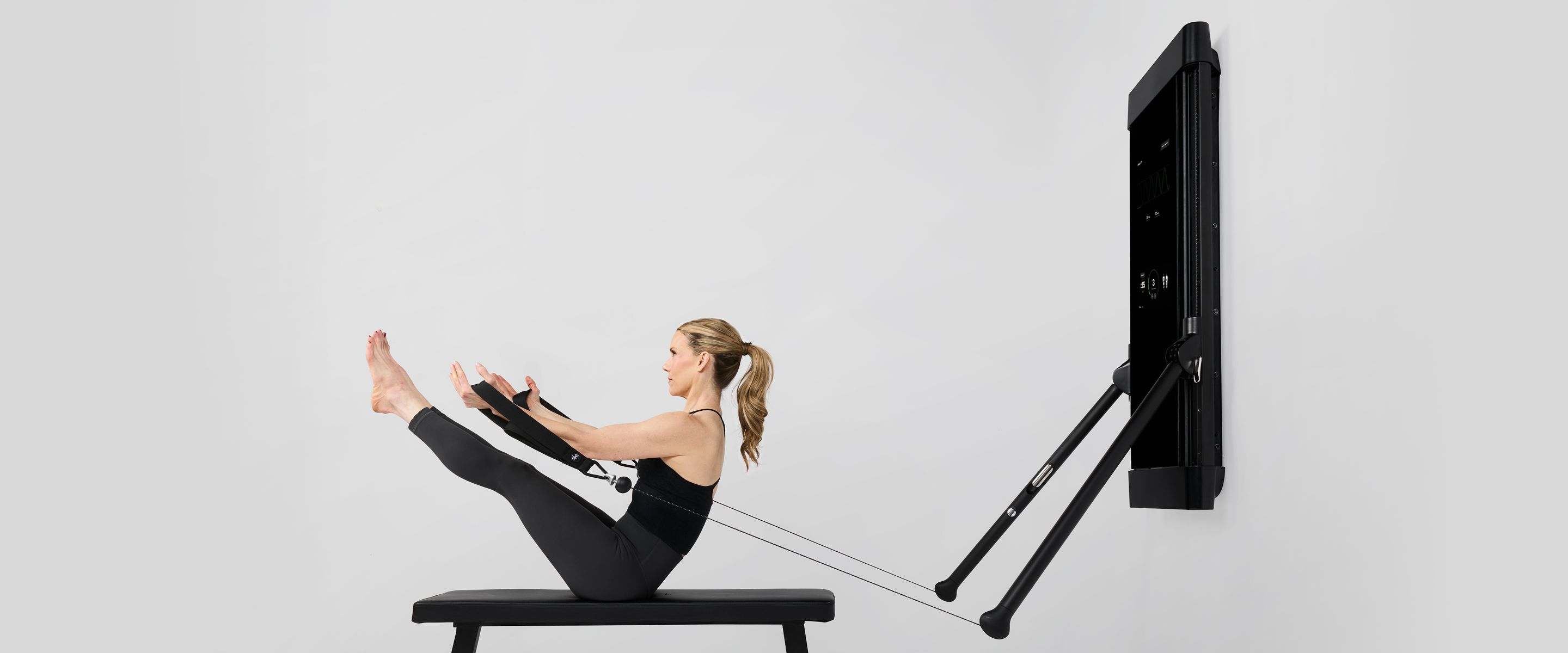 Woman exercising on a Tonal 2 machine doing Pilates reformer exercises. 