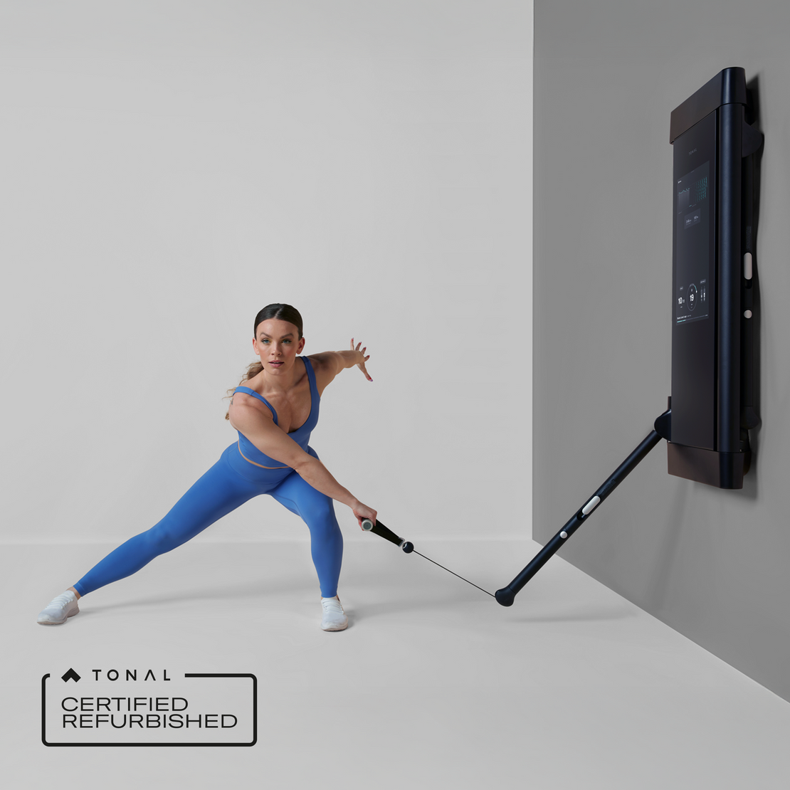 Woman exercising with a certified refurbished Tonal fitness device against a gray wall.