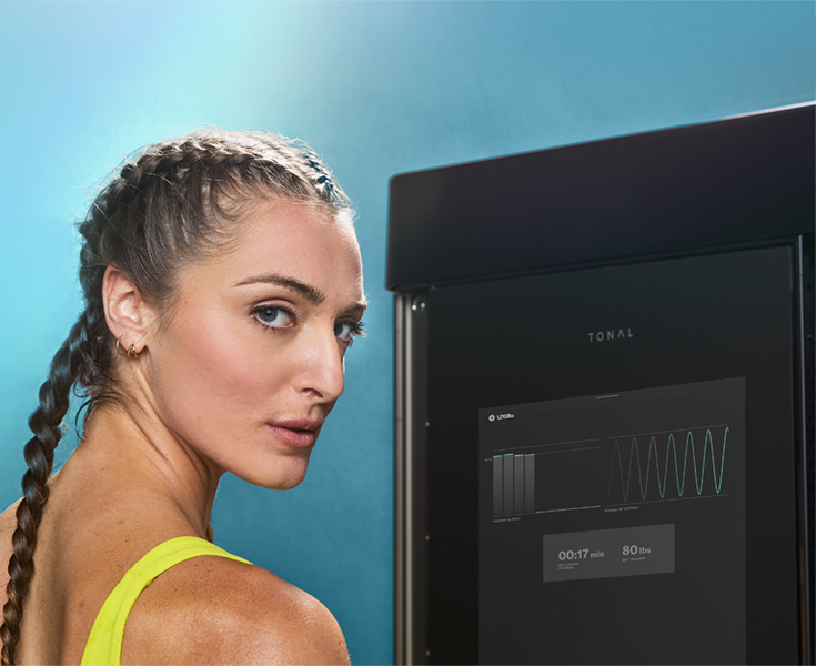 Woman with braided hair looking at camera at her Tonal machine